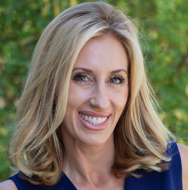 Smiling woman with blonde hair outdoors.