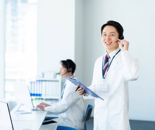 Smiling male doctor showing an OK gesture in a bright medical office.