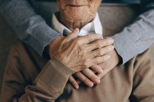 Elderly couple holding hands showing affection and support.